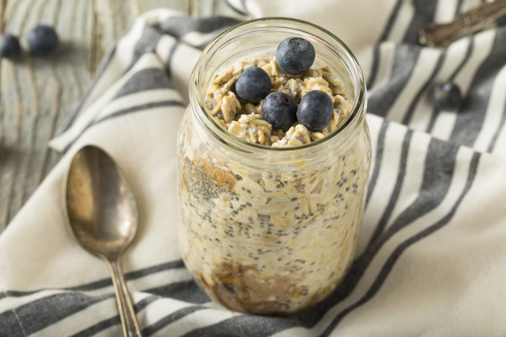 jar of overnight oats on a towel next to a metal spoon